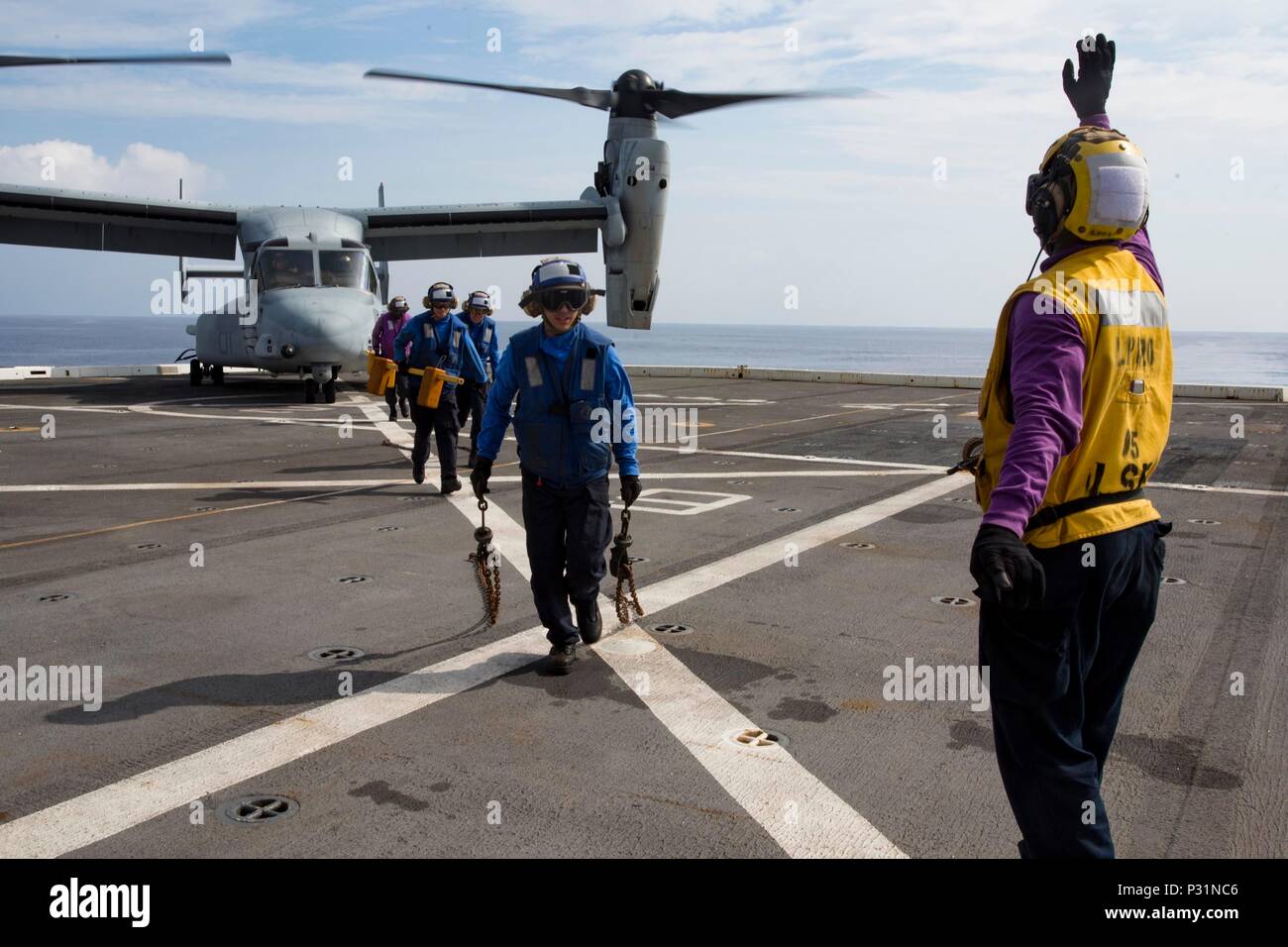 ABOARD USS GREEN BAY (LPD-20), At Sea (Aug. 22, 2016) – U.S. Navy Petty Officer 2nd Class Torien Collins, an aviation boatswain's mate, directs sailors away from a U.S. Marine Corps MV-22B Osprey tiltrotor aircraft from Marine Medium Tiltrotor Squadron 262 (reinforced), 31st Marine Expeditionary Unit, on the flight deck of the USS Green Bay (LPD-20), at sea, Aug. 22, 2016. Marines of the 31st MEU are currently embarked on ships of the USS Bonhomme Richard Expeditionary Strike Group for a regularly scheduled fall patrol of the Asia-Pacific region. The 31st MEU combines air-ground-logistics into Stock Photo