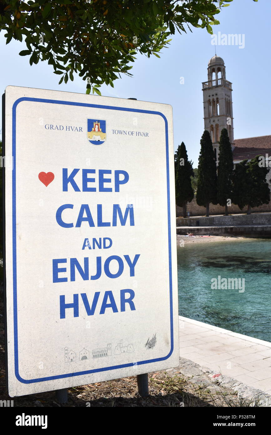 Sign located on Hvar island promenade with the Keep Calm-o-matic theme. Bell tower at the background. Hvar island, Croatia, June 2018 Stock Photo