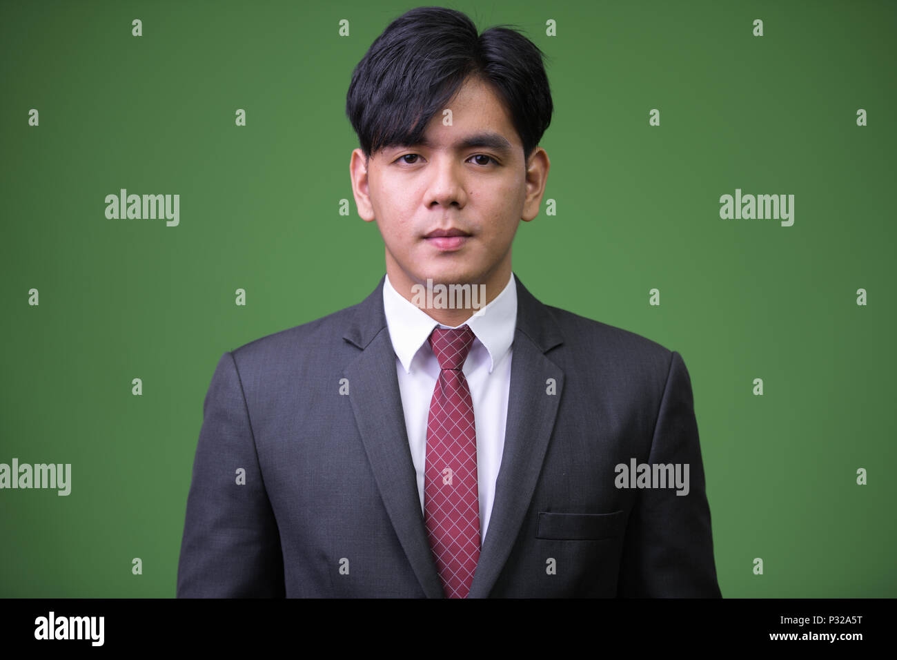 Young handsome Asian businessman against green background Stock Photo