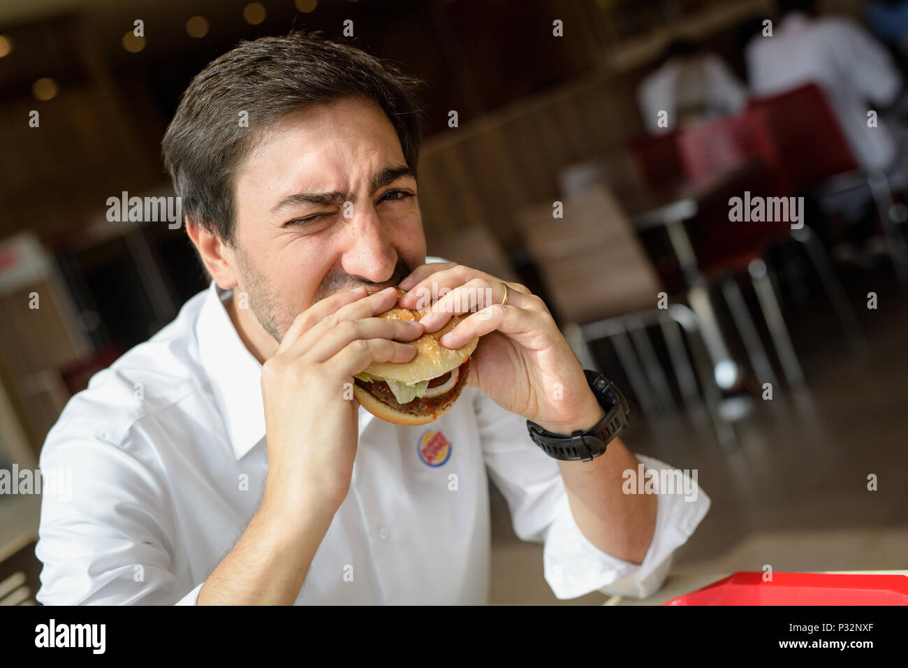15 June 2018, Germany, Munich: Carlos Eduardo Baron, Burger King's manager in Germany, eats a burger during an interview. Photo: Matthias Balk/dpa Stock Photo
