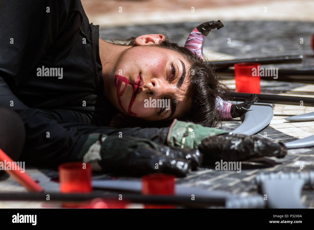 Alicante, Spain. 17th June, 2018. A woman lays on the floor with fake blood in her mouth during a performance where anti-bullfighting protesters demand the abolishment of bullfighting and animal suffering, in Alicante, Spain. Credit: Marcos del Mazo/Alamy Live News Stock Photo