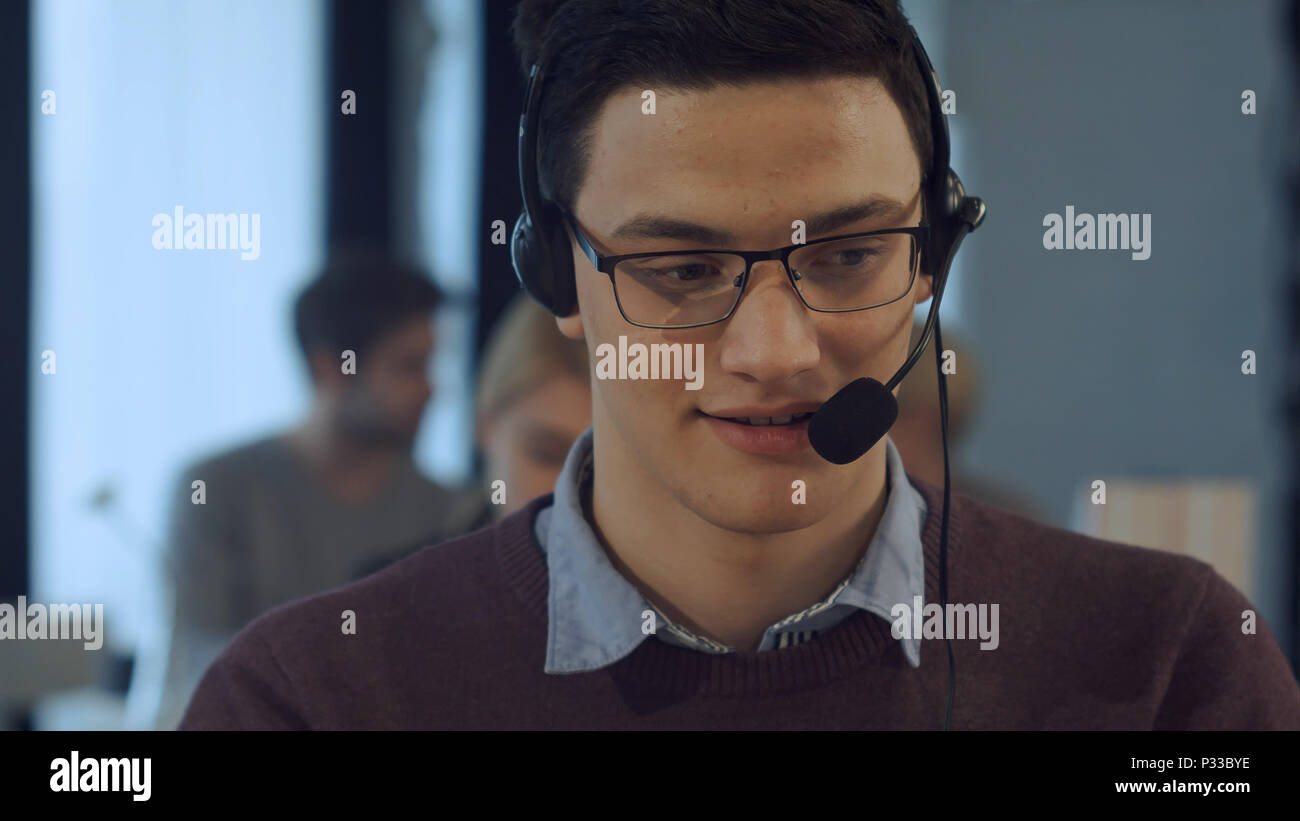 Young man working at a computer in a call centre smiling Stock Photo