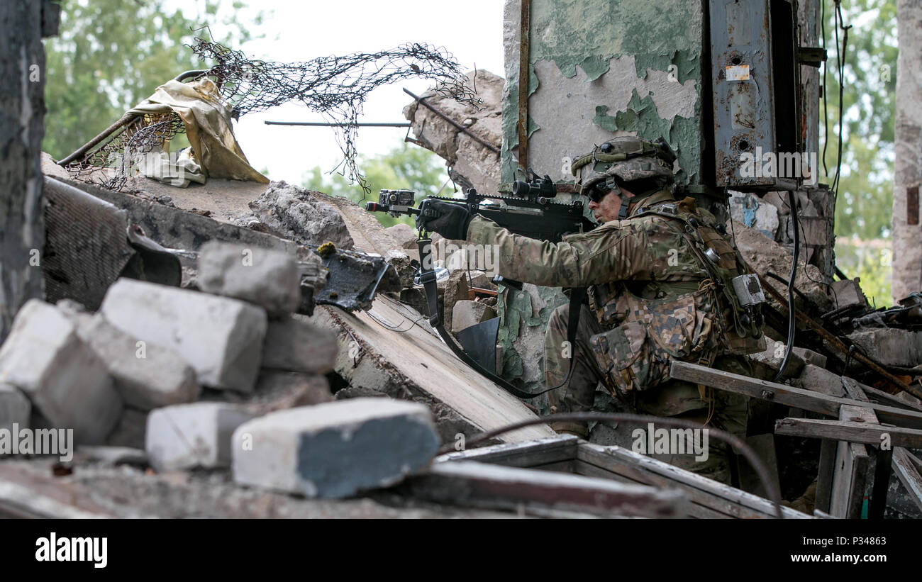 U.S. Army Cadet Kenneth Bass, a cadet studying at Utah Valley University, assigned to US Army Cadet Command, Fort Knox, Ky., takes a defensive position during military offensive urban training (MOUT) while participating in Saber Strike 18 in Skrunda, Latvia, June 12, 2018. Saber Strike is a multinational exercise currently in its eighth year. This year's exercise, which is scheduled to run from June 3-15, tests participants from 19 countries on their ability to work together to promote stability in the region and improve each units ability to perform their designated missions. (U.S. Army photo Stock Photo