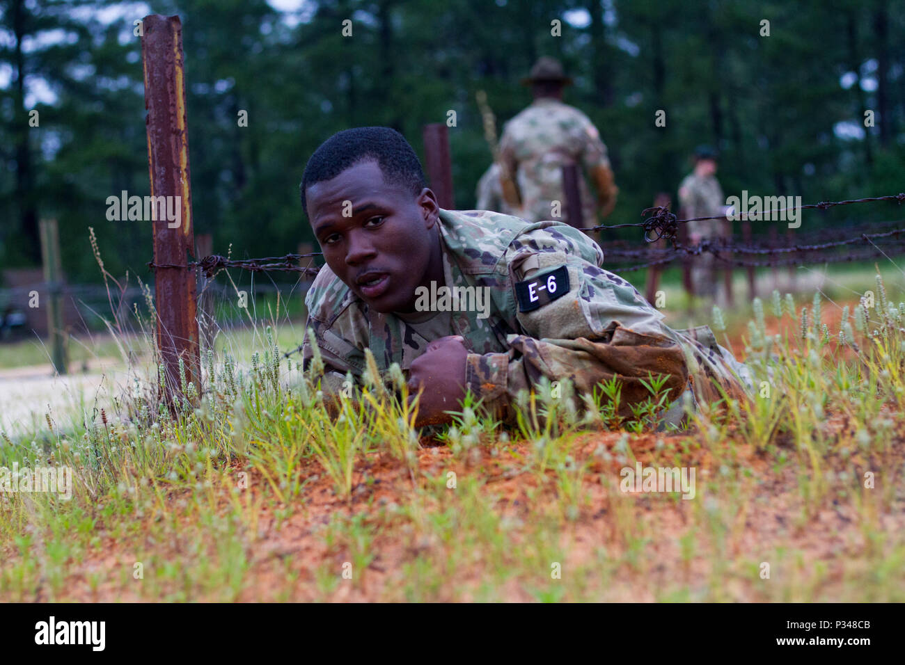 U.S. Army Reserve Pfc. Ladarius Smith, a human resources specialist from Lapine, Alabama, with the Headquarters, Gulf Division, 84th Training Command (Unit Readiness), performs a low crawl on obstacle four of the Fort Bragg Air Assault School Obstacle Course. Touching the barbed wire with any part of their body during this lane results in disqualification, requiring the competitor to be returned to the beginning of the lane to try again or continue with a loss of points.  Thirty-six warriors continue to vie for the title of United States Army Reserve Best Warrior during the grueling multifacet Stock Photo