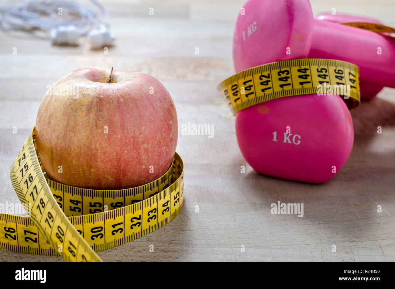 still life and close up with apple, pink weight, yellow tape measure. fitness and lifestyle concepts. Stock Photo