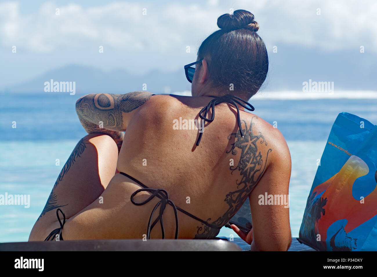 Girl with tattoos sunbathing in Tahiti Stock Photo