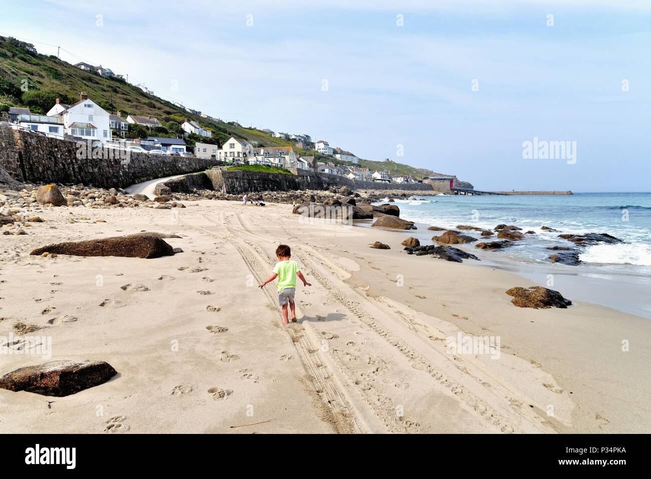 Little boy running along sandy beach at Sennen Cove Cornwall England UK Stock Photo