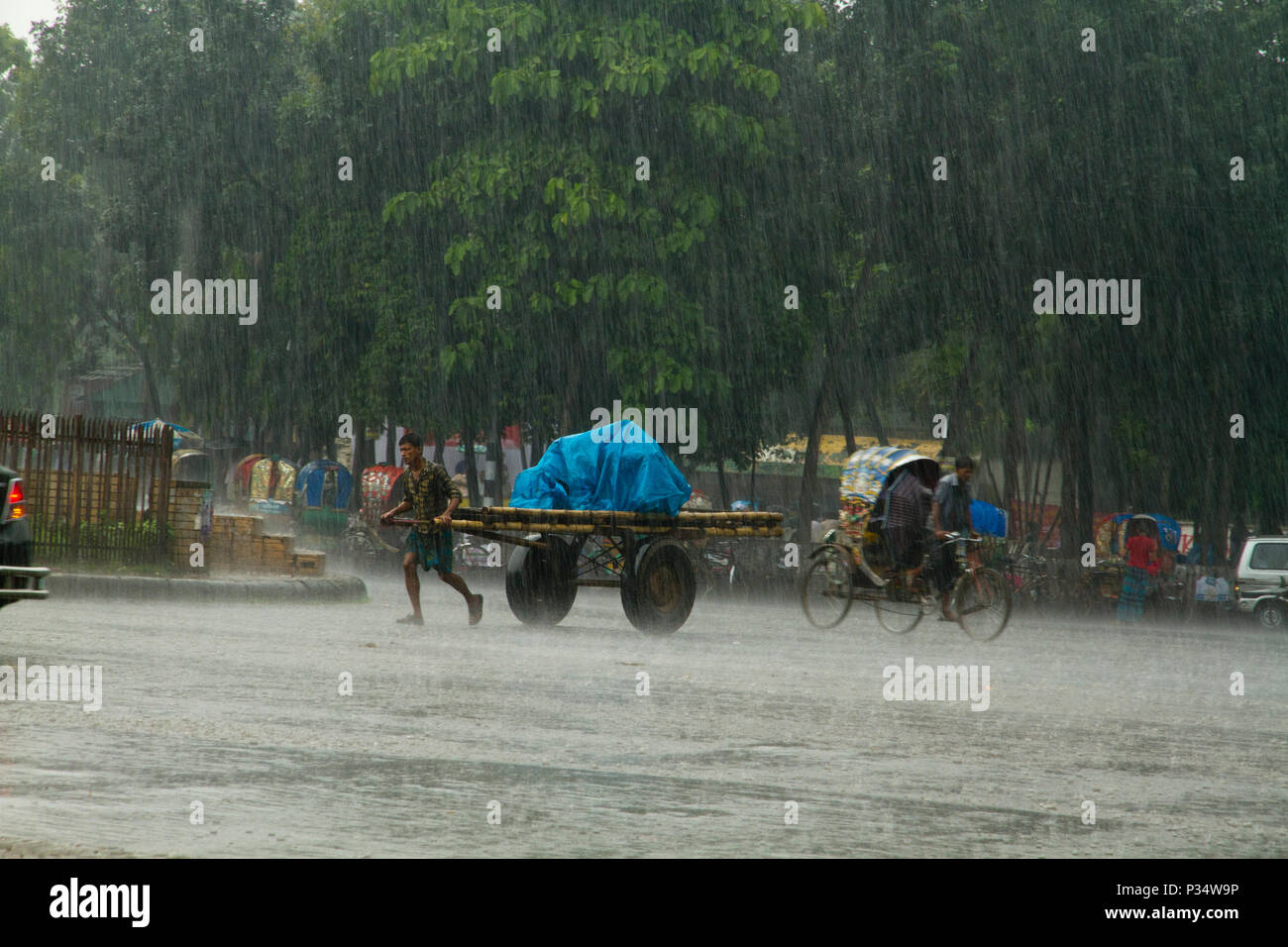 Rickshaws and vehicles on the street during heavy rain. Dhaka, Bangladesh. Stock Photo