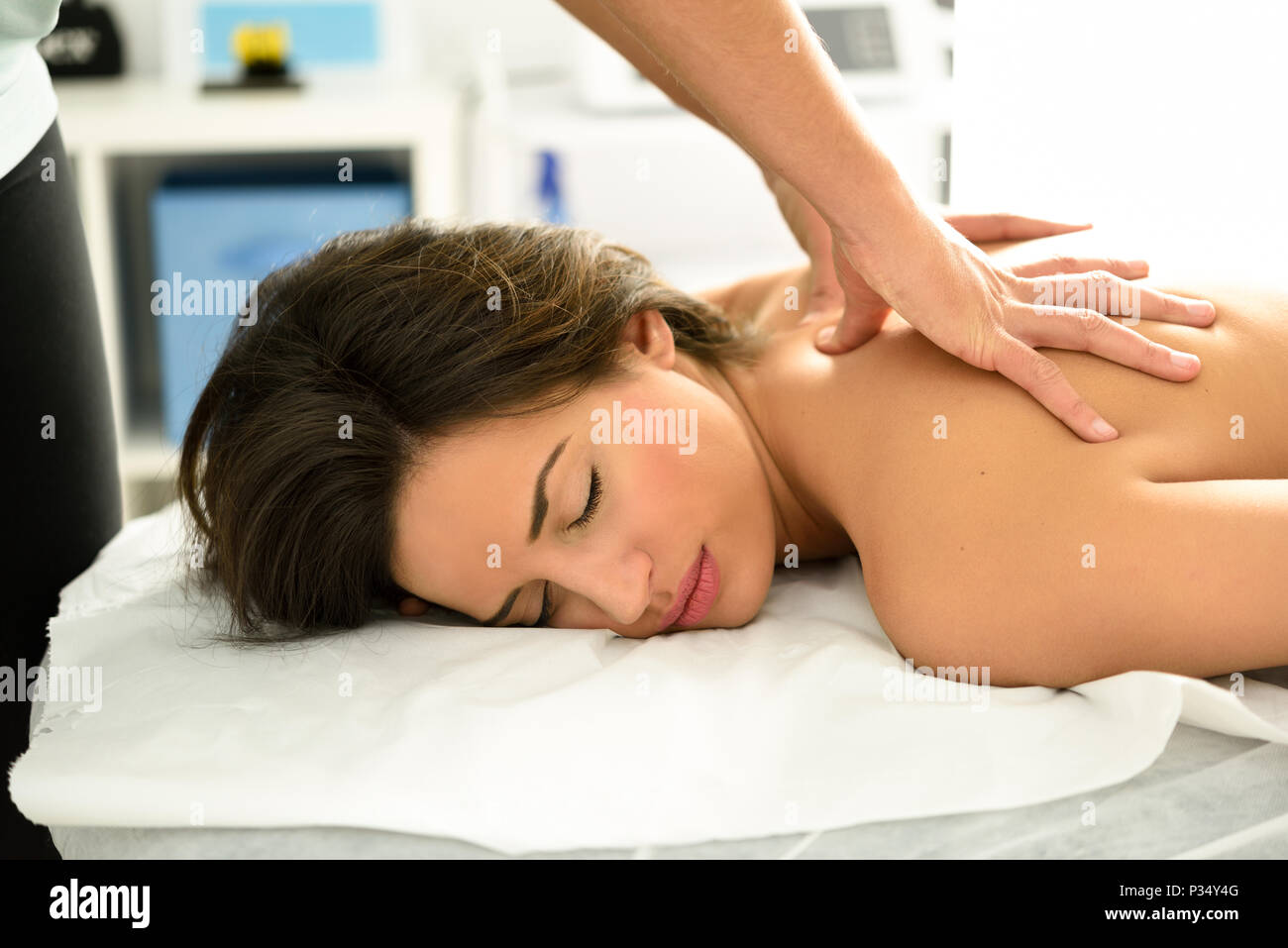 Young woman receiving a back massage in a spa center. Female patient is receiving treatment by professional therapist. Stock Photo