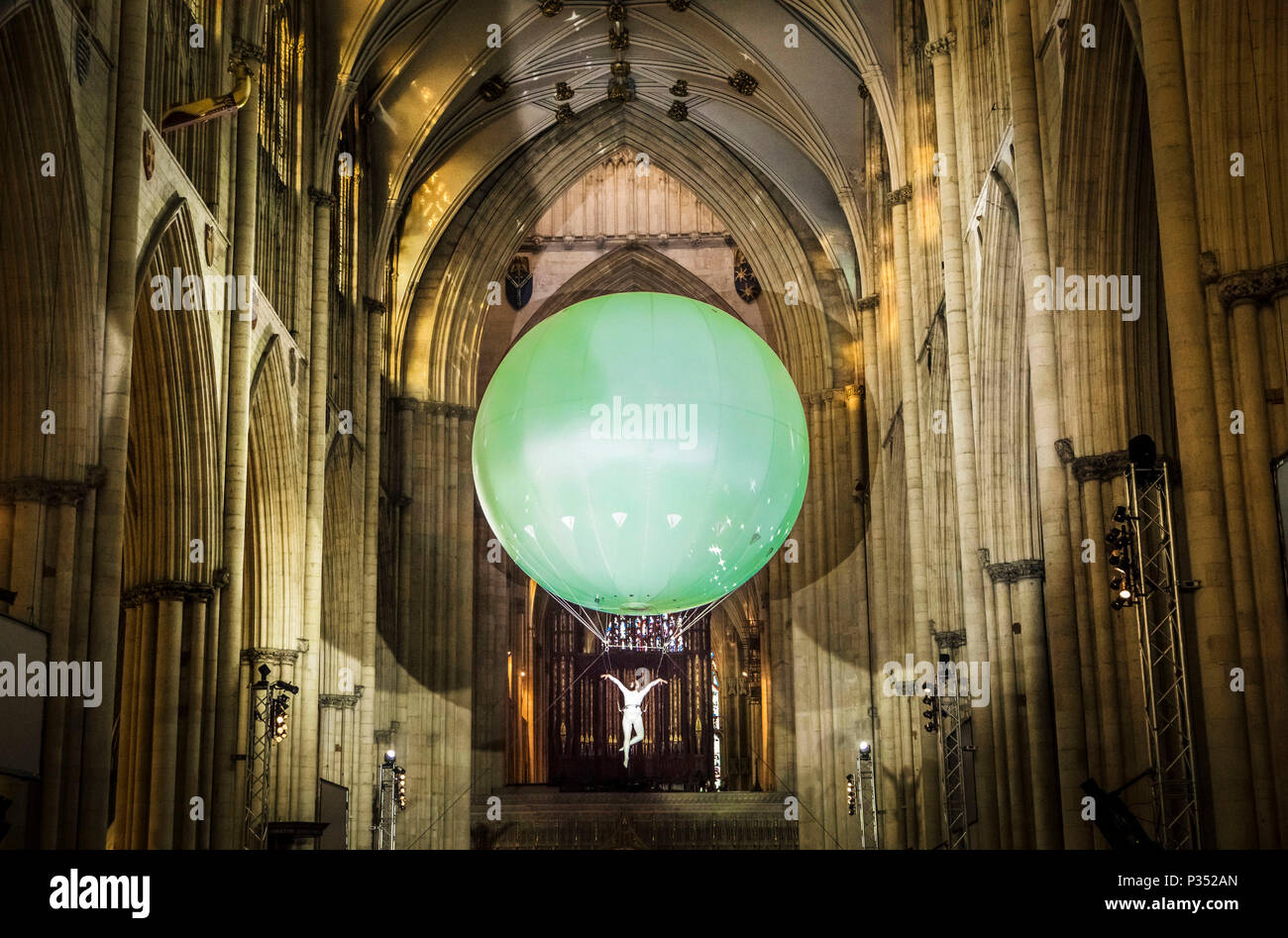 An acrobat performs suspend beneath a giant inflatable ball floating through York Minster's nave, during a performance of Heliosphere by The Dream Engine. Stock Photo