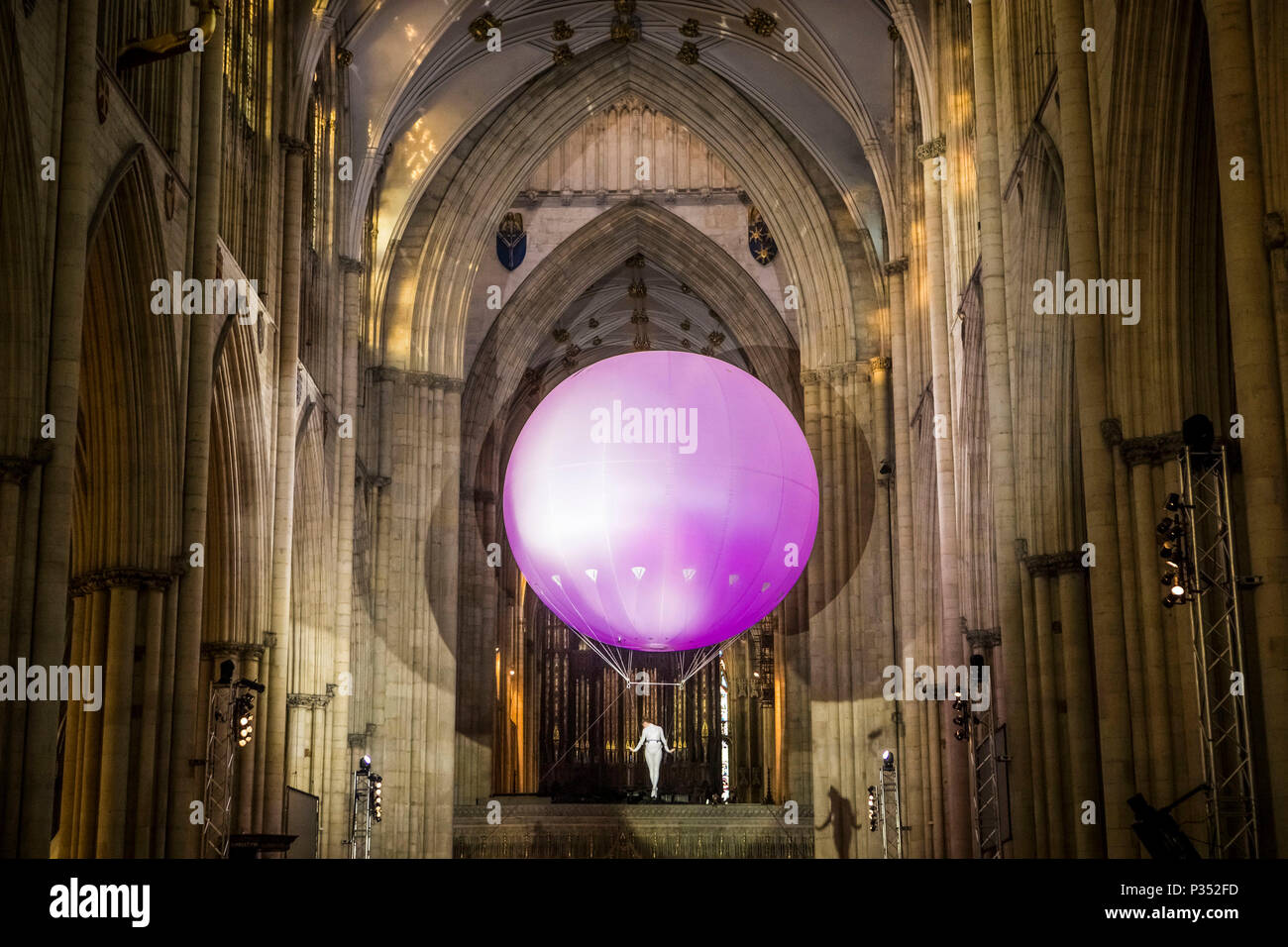An acrobat performs suspend beneath a giant inflatable ball floating through York Minster's nave, during a performance of Heliosphere by The Dream Engine. Stock Photo