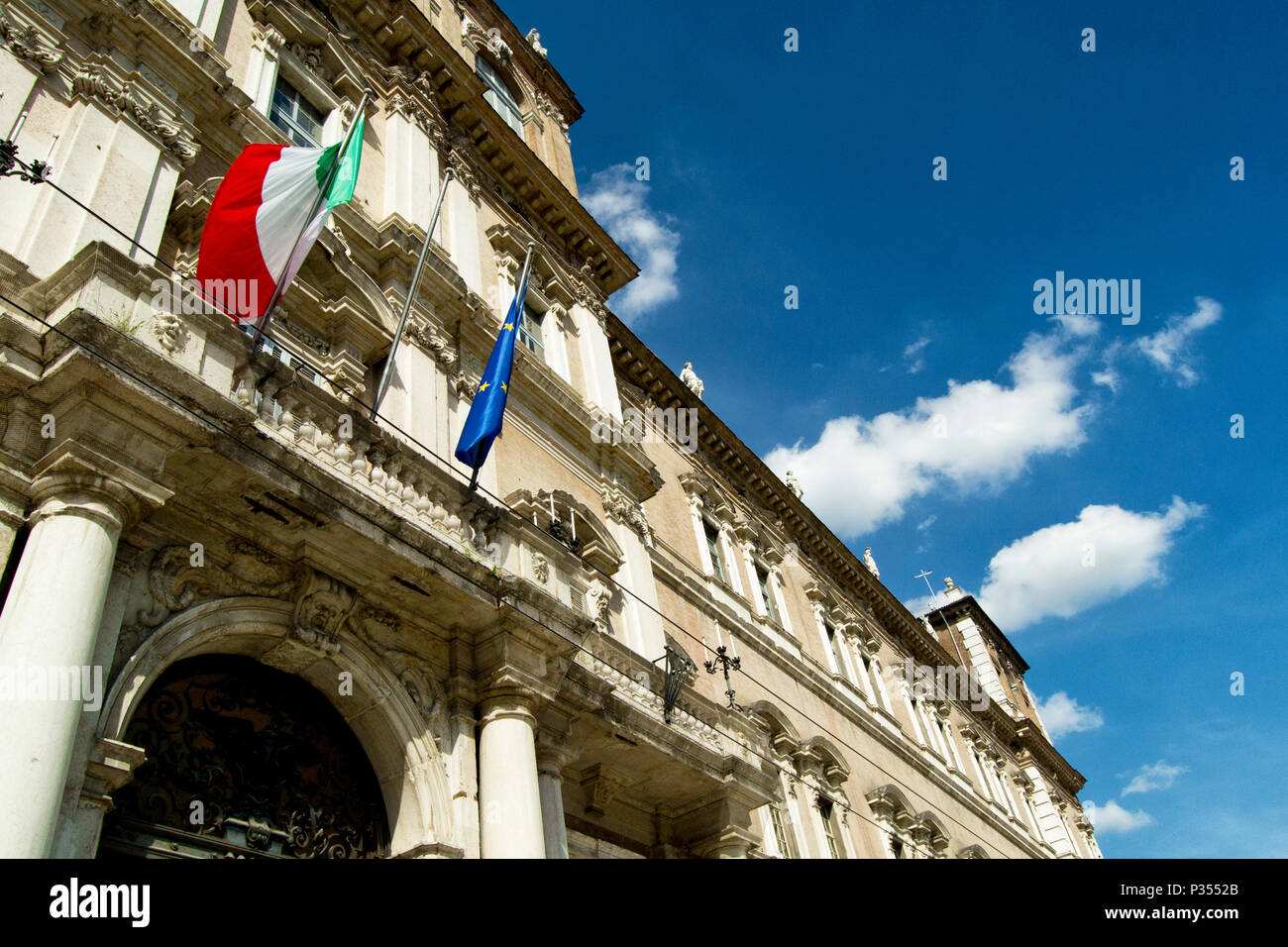 Italian and EU flags on a balcony of the italian army academy with blue sky and white clouds. Modena, Italy Stock Photo