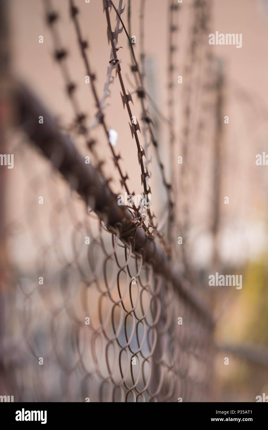 A closeup with blurred background of wire lattice fencing and barbed wire with backbround graffiti. Johannesburg inner city Stock Photo