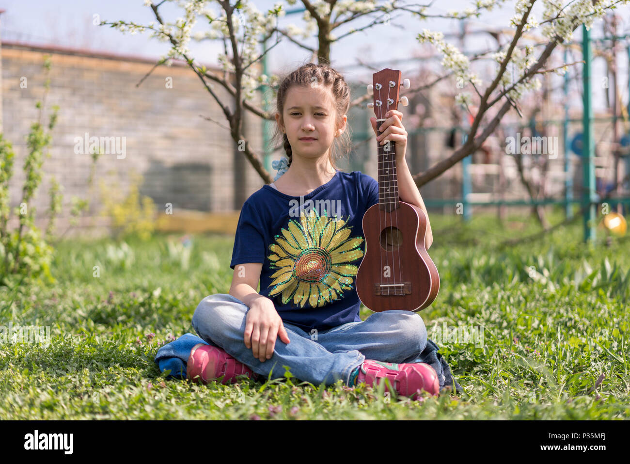 A little girl playing ukulele in the garden Stock Photo Alamy