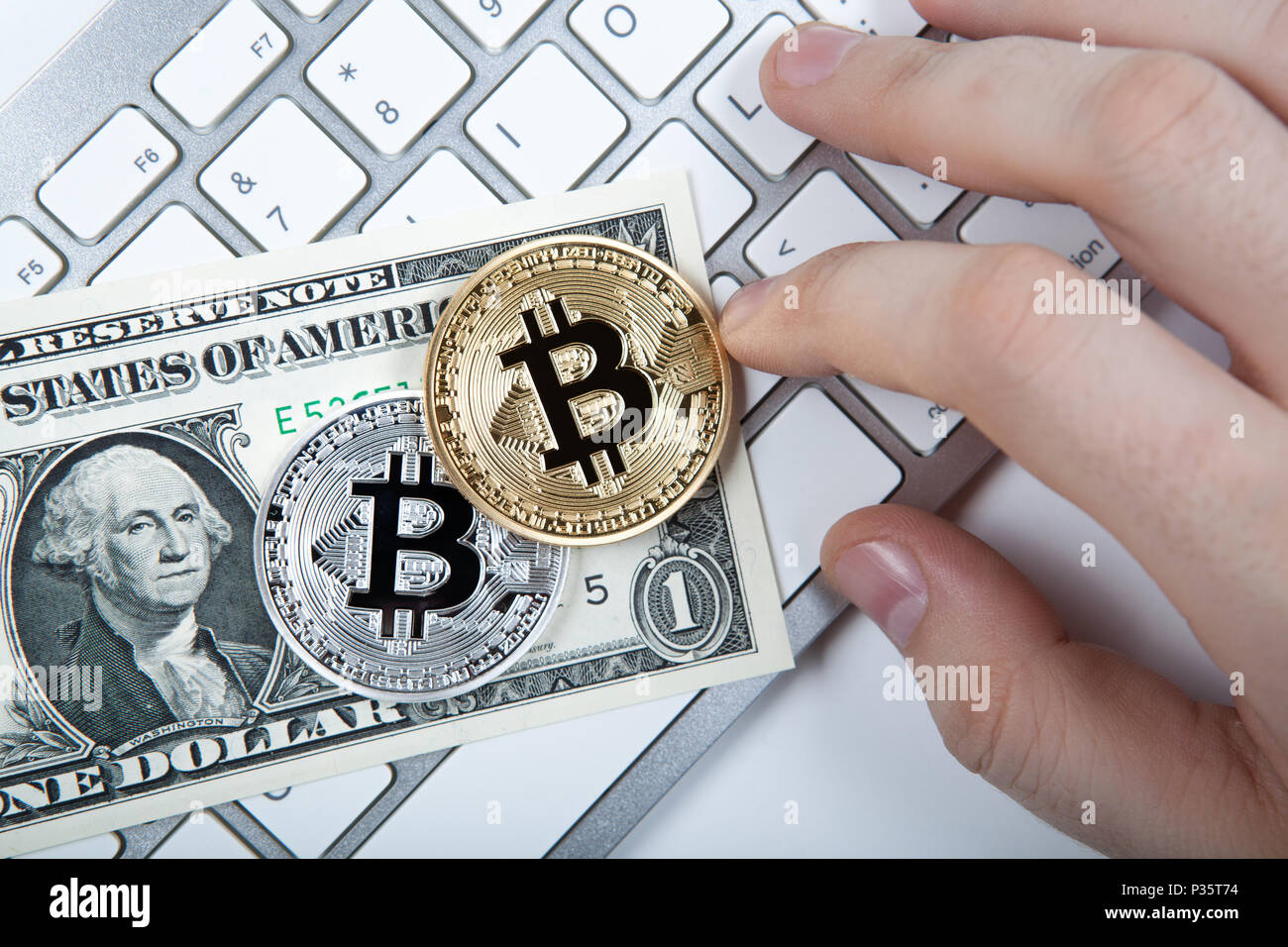 two coins of bitcoin and a dollar bill and human hand on laptop keyboard  close up Stock Photo - Alamy