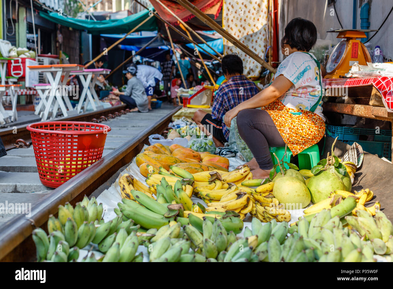 Vendors at famous Maeklong railway market selling fruit and vegetables at railway tracks, Samut Songkhram province, Thailand Stock Photo
