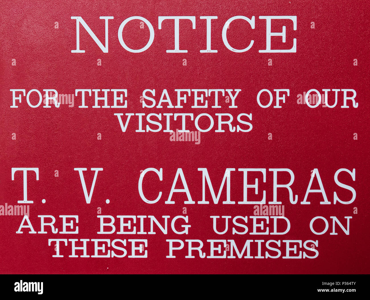 Red and white sign stating: NOTICEFOR THE SAFETY OF OUR VISITORST.V. CAMERAS ARE BEING USED ON THESE PREMISES Stock Photo
