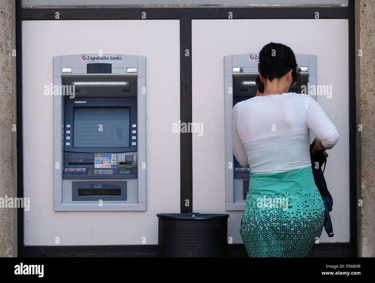 Unidentified girl withdrawing money from an ATM machine in city center. More than 4,000 ATM machines has been installed across Croatia since 1990. Stock Photo