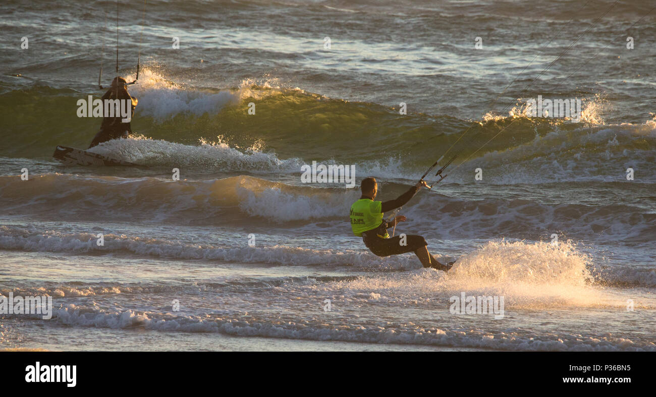 kiteboarding or kitesurfing riding the waves at sunset at Kite Beach