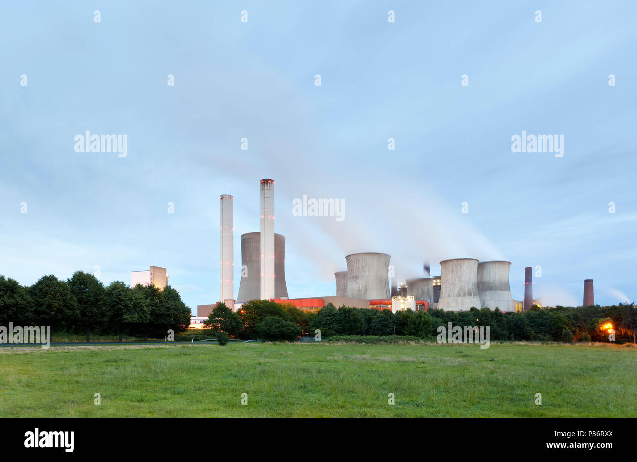 A lignite power station with night blue sky and a lot of steam. Power plant Niederaussem features the tallest cooling tower in the world. Stock Photo