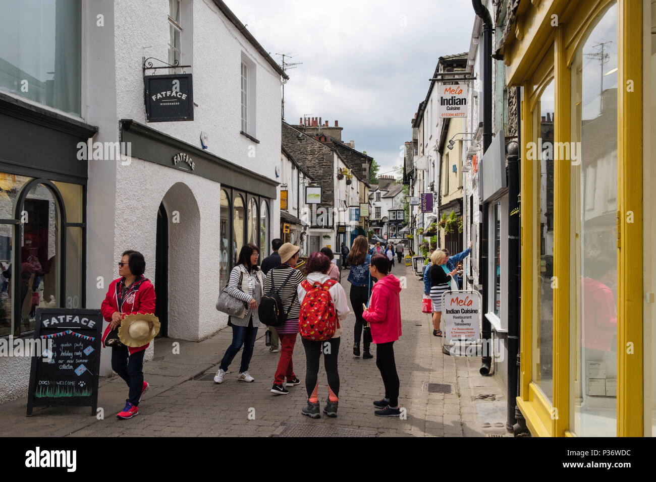 Tourists and shops on narrow street in old Lake District town. Ash Street, Bowness on Windermere, Cumbria, England, UK, Britain Stock Photo