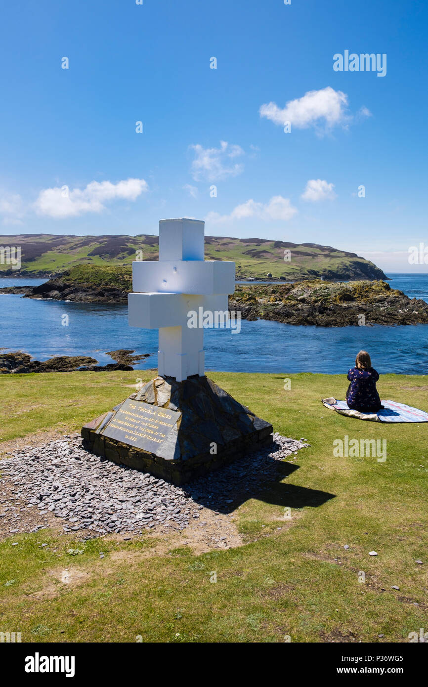 The Thousla Cross at southern tip on south coast with woman tourist sat looking at view to Calf of Man island. Kitterland, Isle of Man, British Isles Stock Photo
