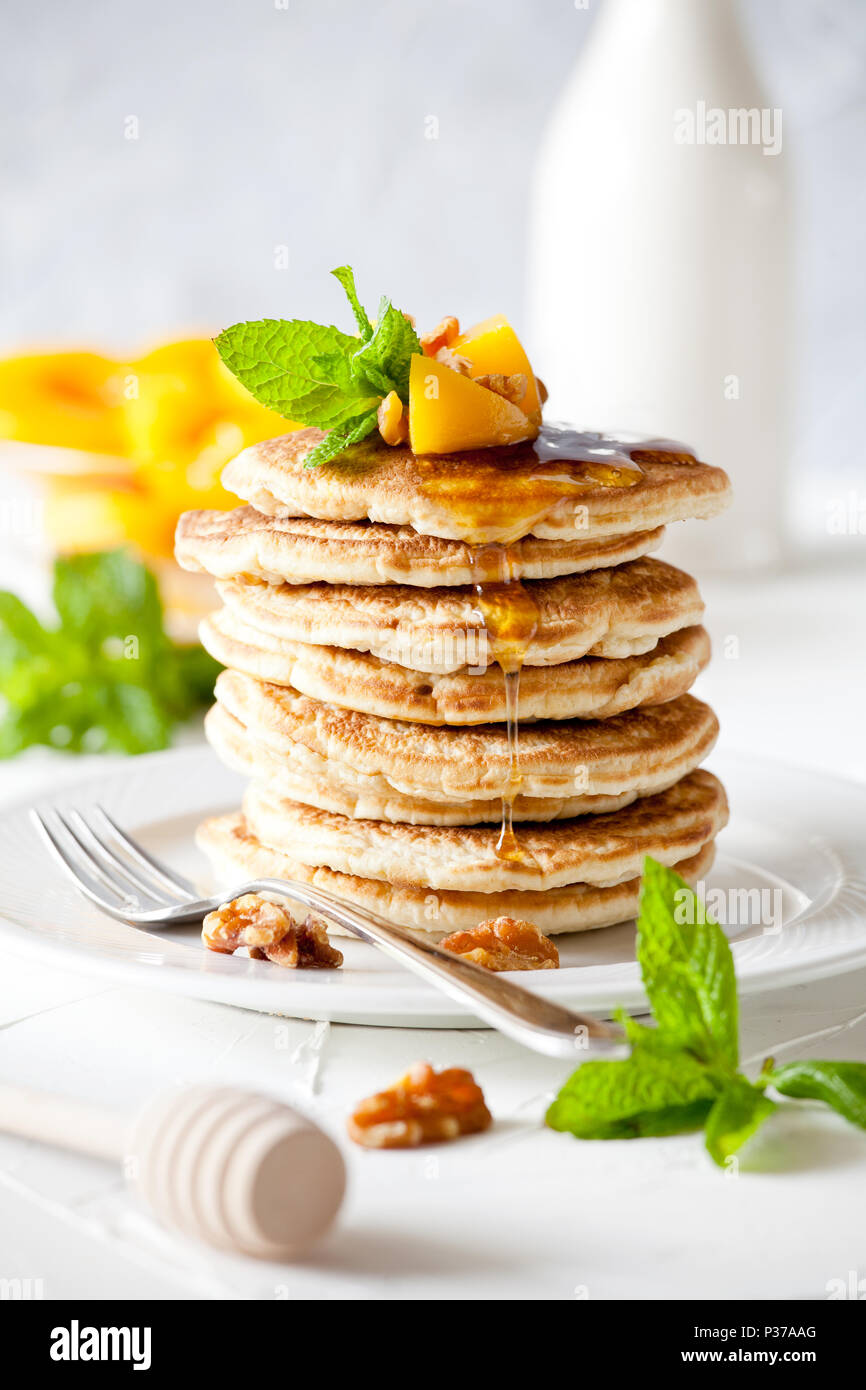 Bunch of pancakes with poached peaches and nuts Stock Photo