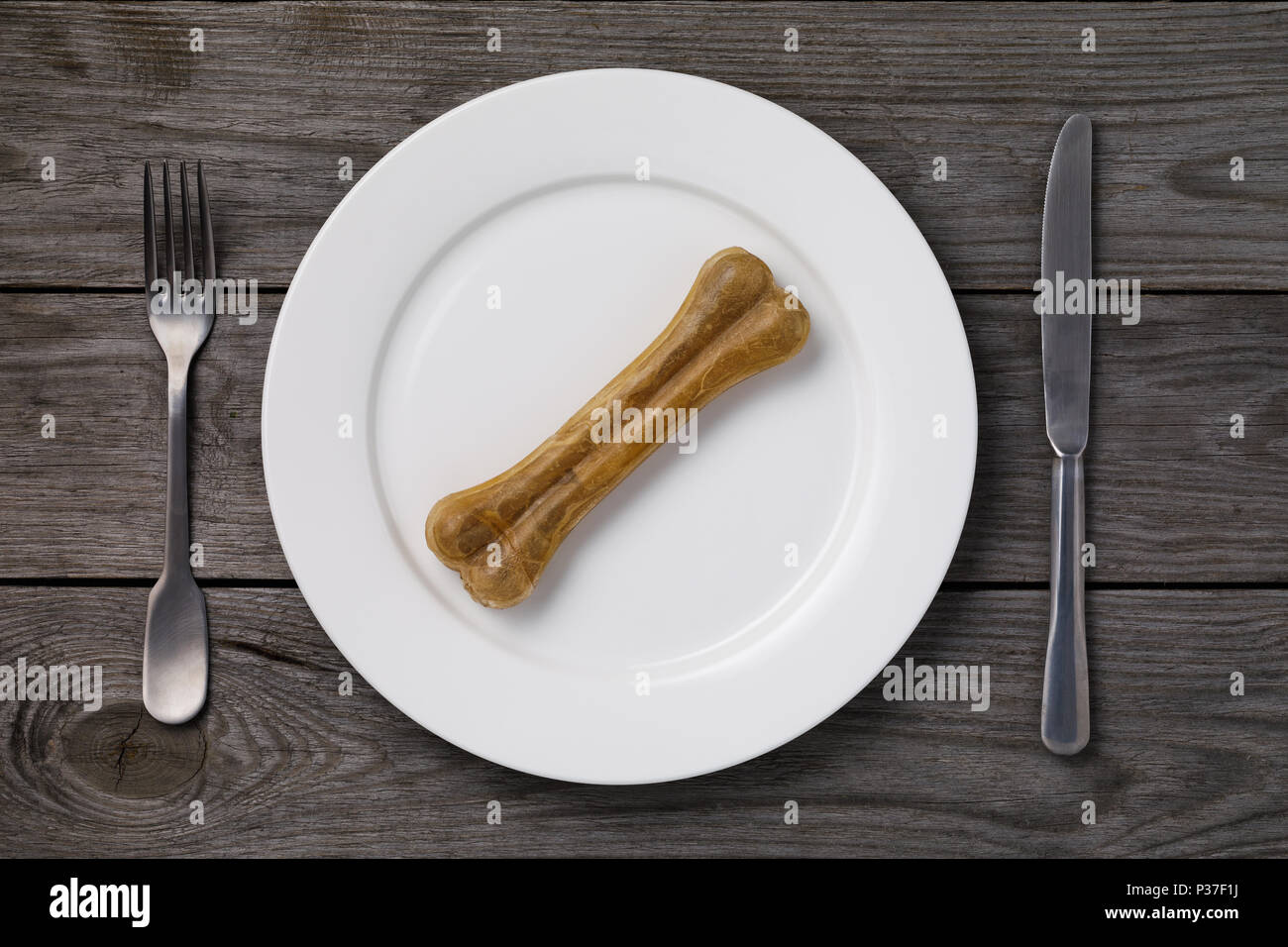 There is nothing to eat: a bone in a white plate on a wooden table, a top view. Hungry time Stock Photo
