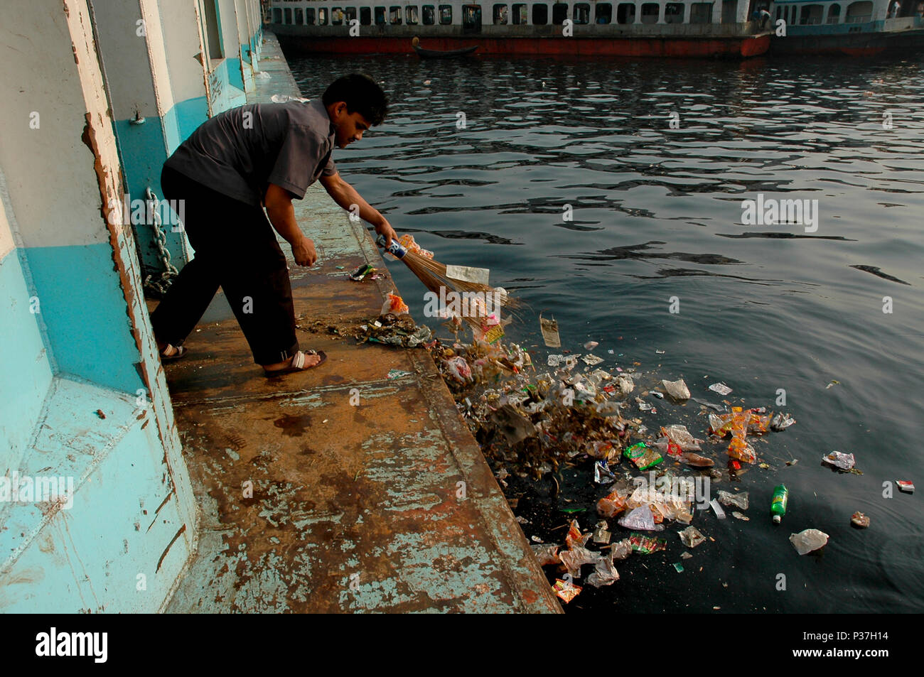 A man sweeps floor of the launch and puts rubbish on the Buriganga