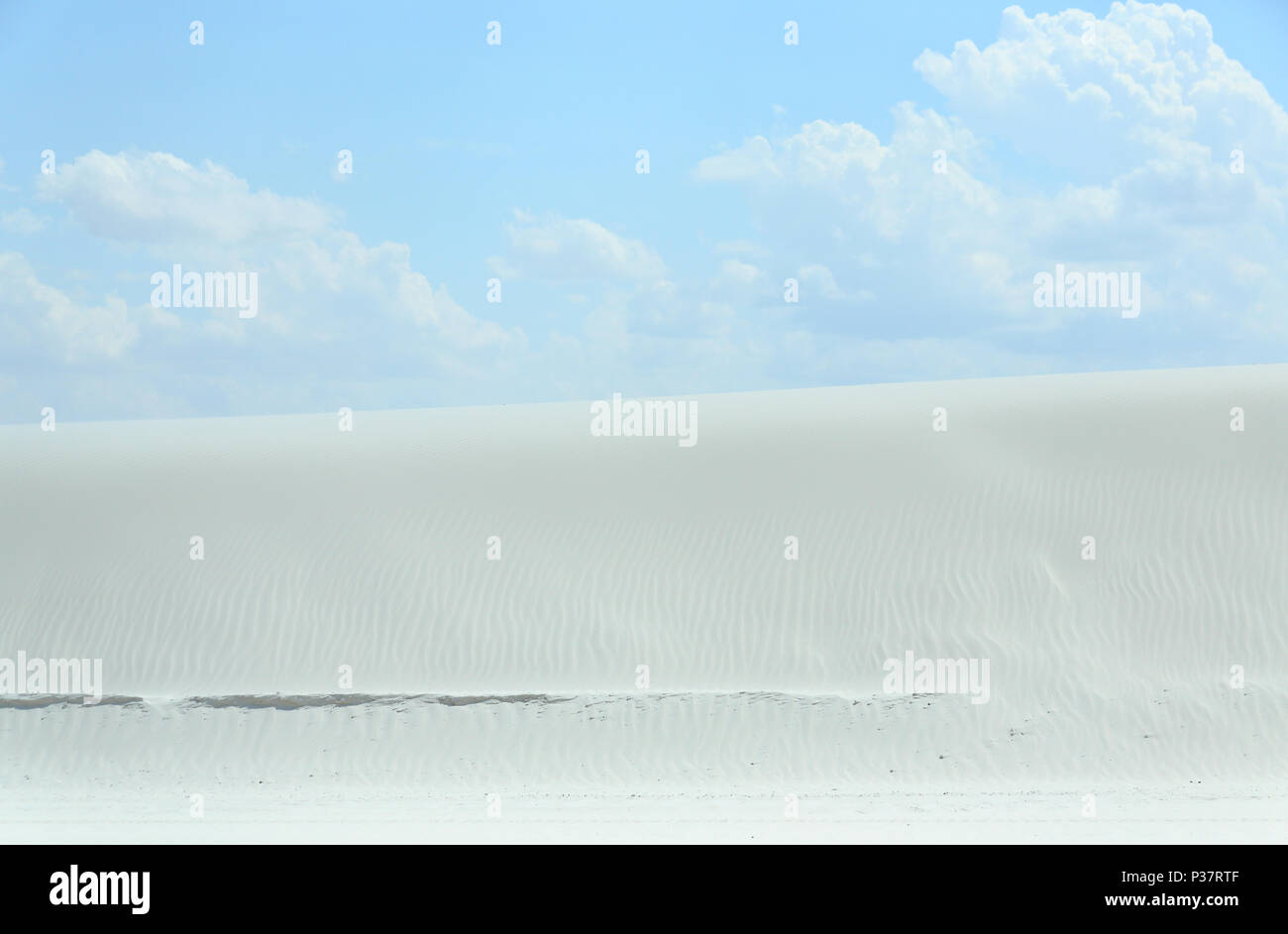 White sand dune with wind formed ripples on a day with blue skies and clouds Stock Photo