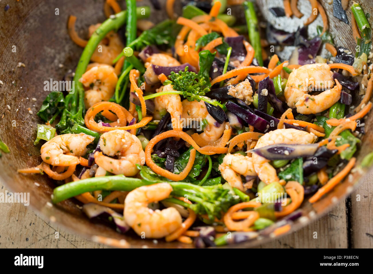Stir fry with carrots, red cabbage, broccoli, kale, edamame, spring onions, seeds & prawns Stock Photo