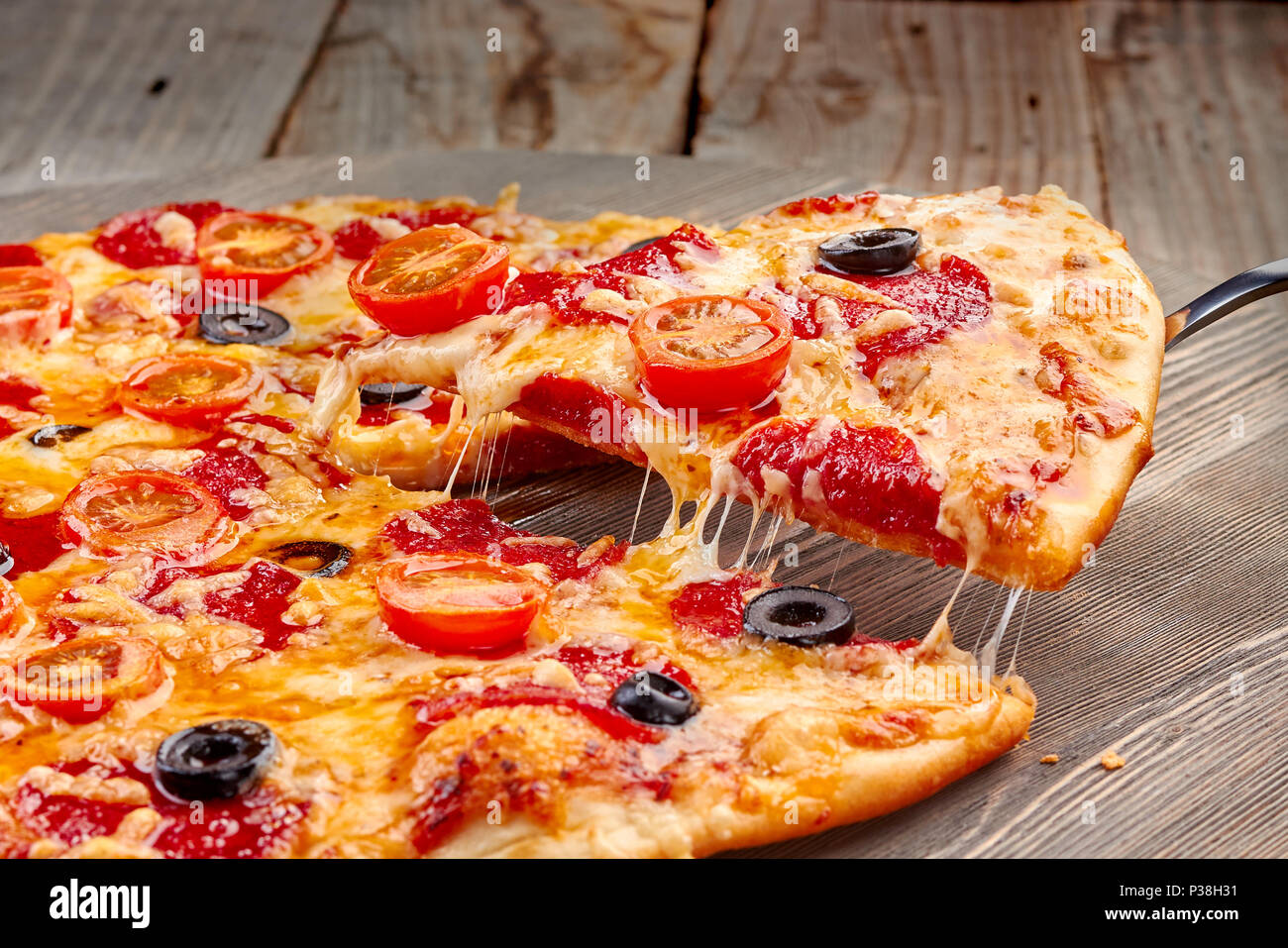 Lifted pepperoni pizza slice with melted cheese Stock Photo