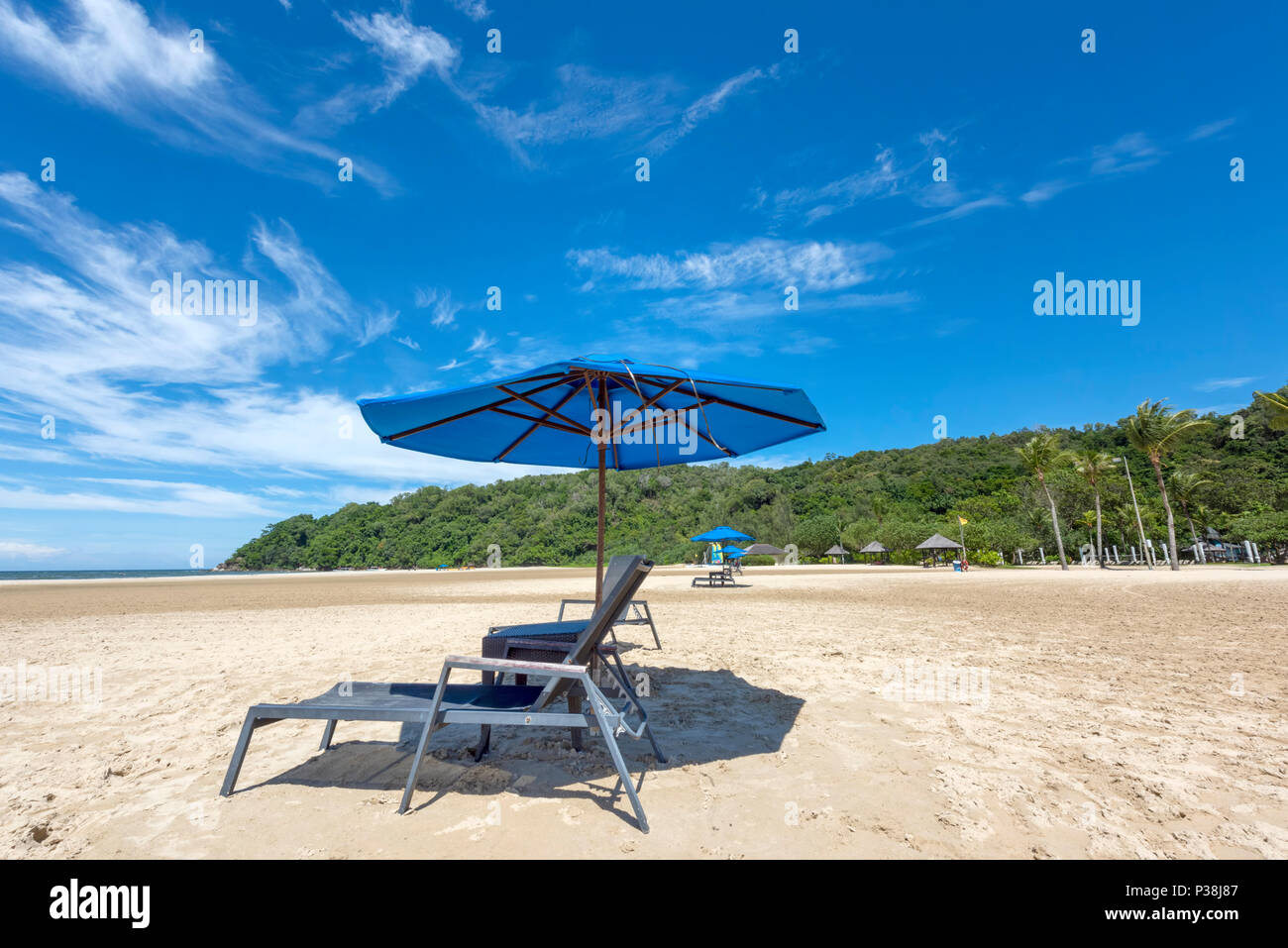 Sunbeds and Parasol on a white sand beach at the Shangri La Rasa Ria Hotel and Resort in Kota Kinabalu, Borneo on the edge of the South China Sea Stock Photo