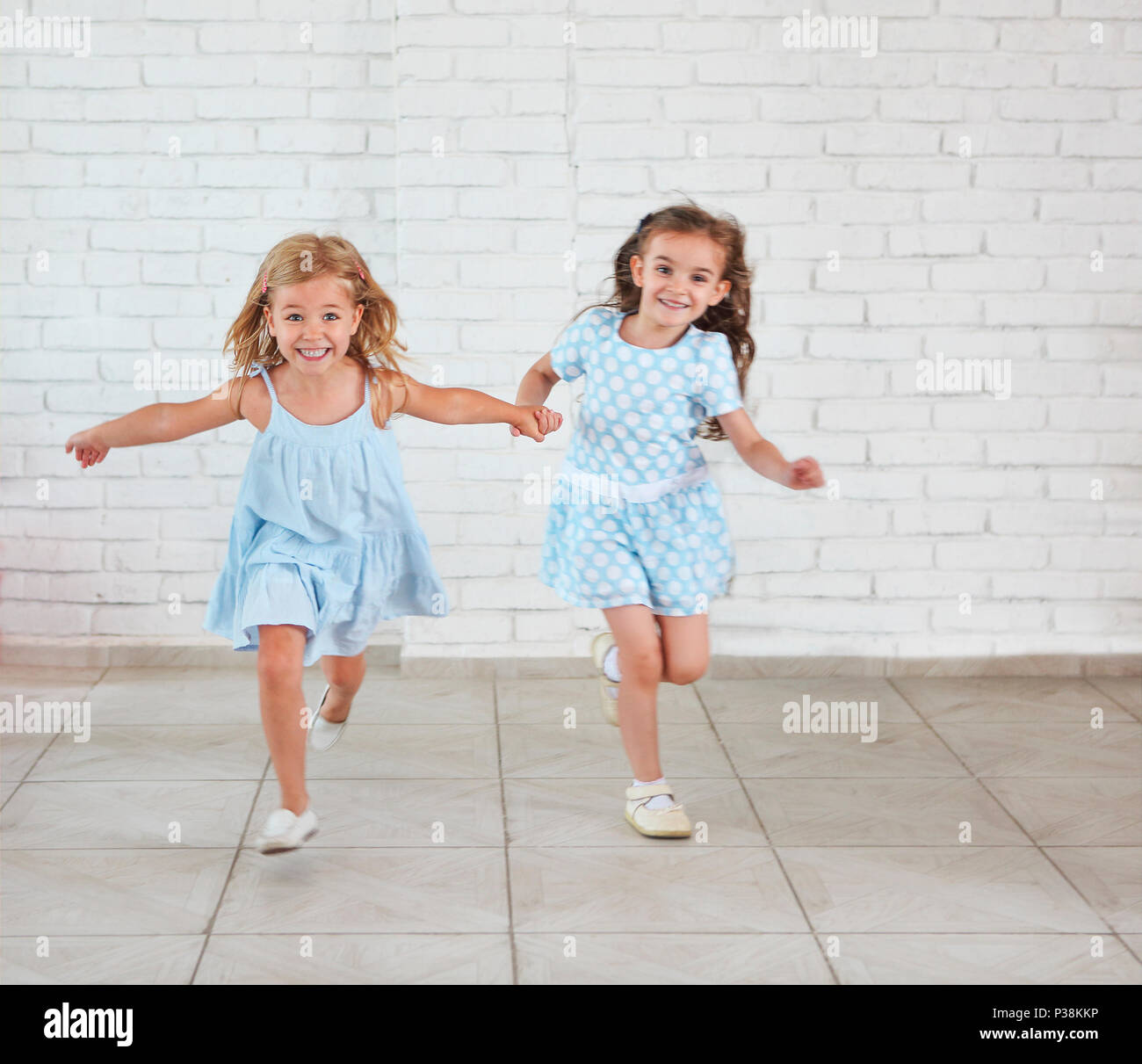 Two small girls playing and running indoors together Stock Photo