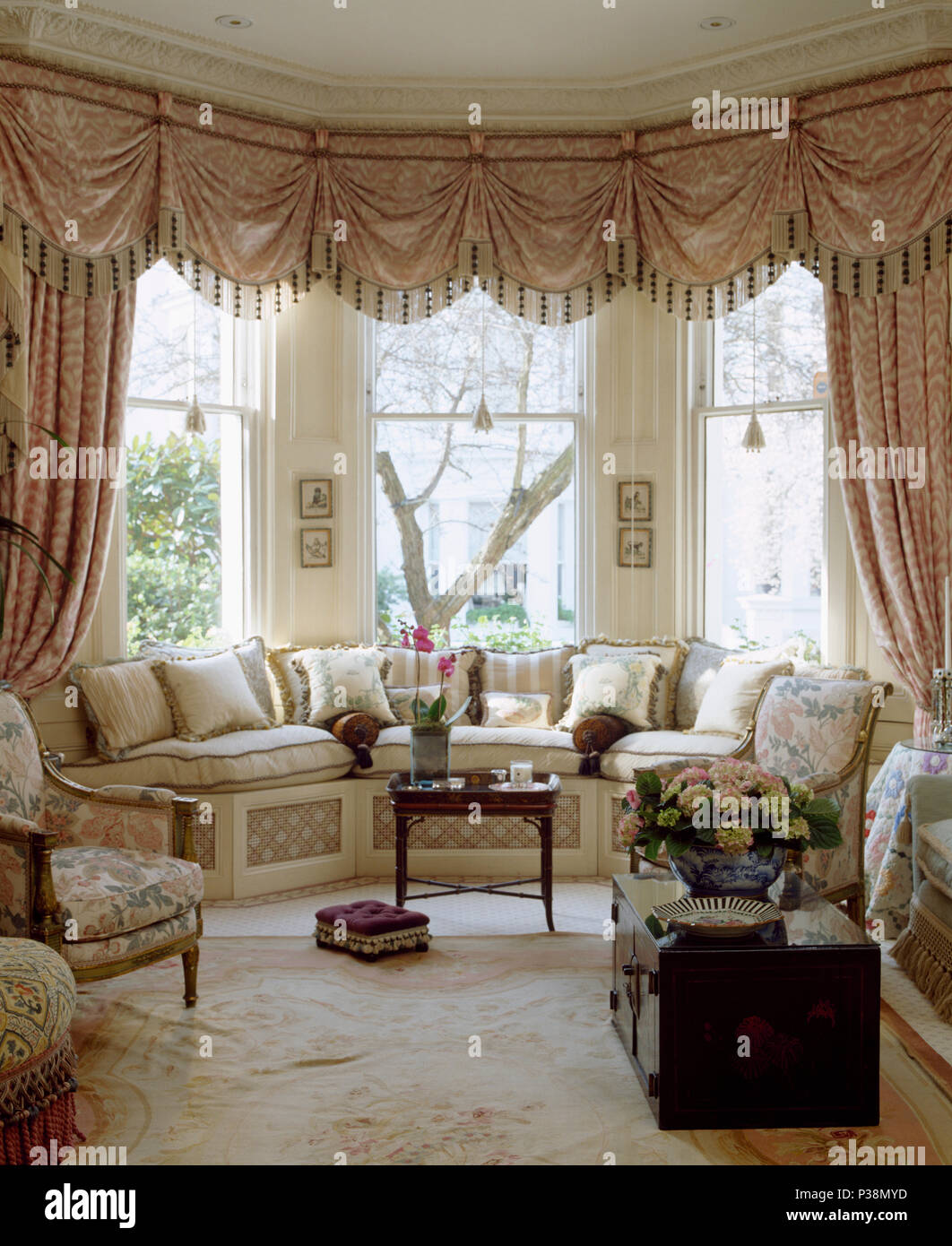 Ornate Swagged Pelmet And Silk Curtains On Bay Window In Townhouse Living Room With Cream Cushions On Window Seat Stock Photo Alamy