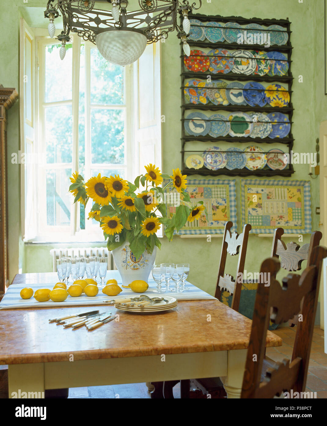 Vase Of Yellow Sunflowers On Table In Tuscan Dining Room With Colourful Pottery Plates On Wall Shelves Stock Photo Alamy