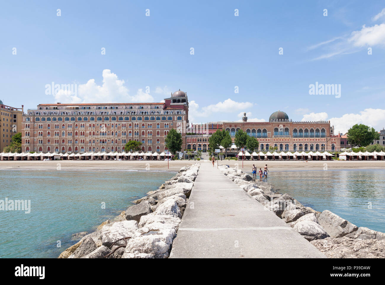 View along the breakwater of the Hotel Excelsior and beach with cabanas or huts, Lido di Venezia, Lido Island, Venice, Veneto, Italy. People bathing i Stock Photo