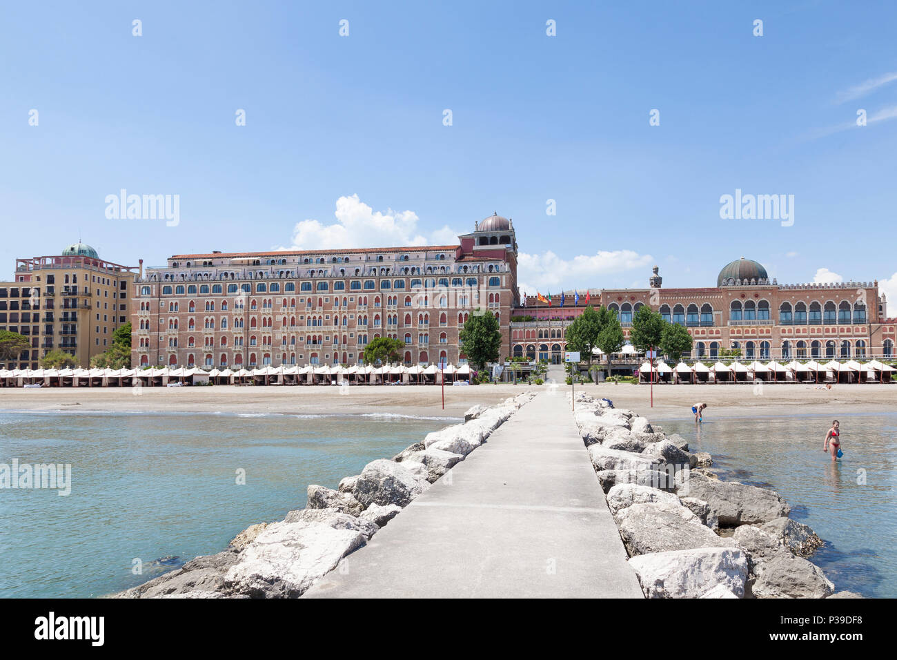 Front facade of Hotel Excelsior with beach and cabanas, Lido di Venezia,  Lido, Venice, Veneto, Italy from a breakwater, Morrish architecture. Stock Photo
