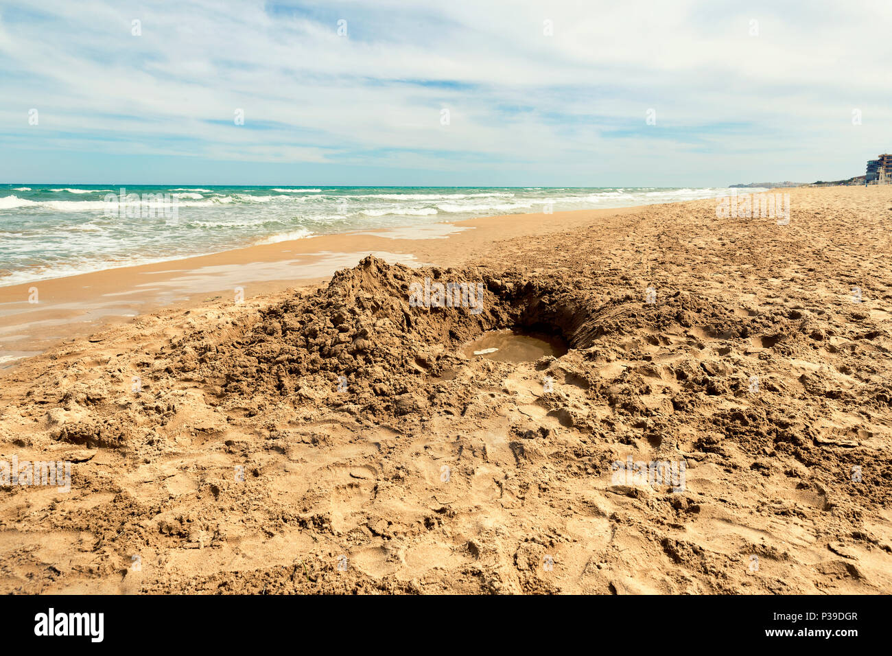sea shore with hole excavated into the sand, guardamar del segura beach. Alicante. Spain Stock Photo