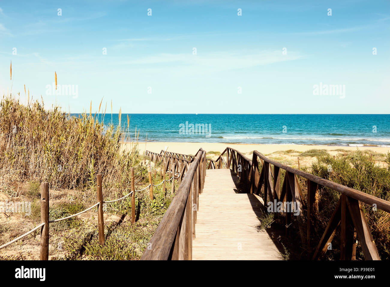 wooden footbridge with railing over dunes to the Guardamar beach in Alicante, Spain Stock Photo