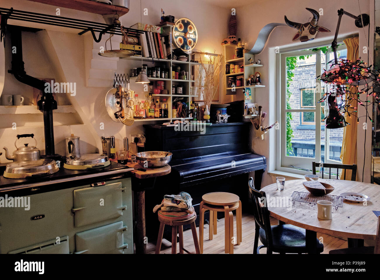 Kitchen with open shelves, retro Aga Cooker, kitchen table, stools & piano  at Adaptable House, 6 Doughty Mews, Bloomsbury, London Stock Photo - Alamy