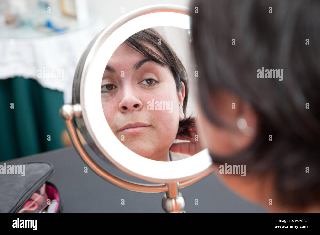 Woman looks at herself in a round dressing table mirror with a natural