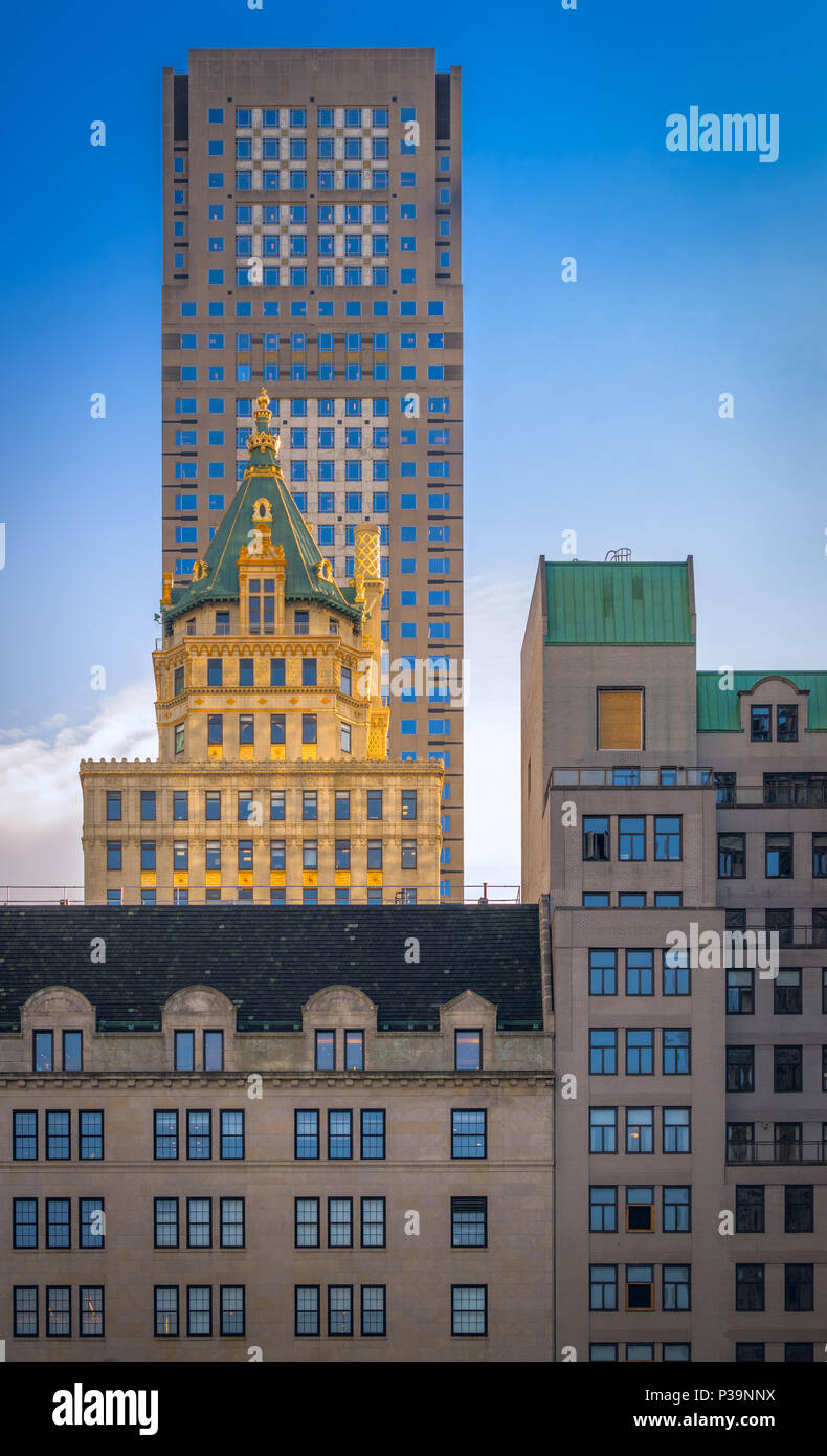 Nested between The Plaza Hotel and 712 fifth Ave, is The Crown Building, glowing golden in the sun, a jewel in Manhattan, New York City, USA Stock Photo