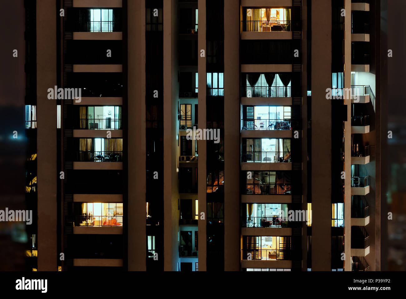 Night scene in big city - front view of high-rise building with windows of apartments in which light is burning. Stock Photo