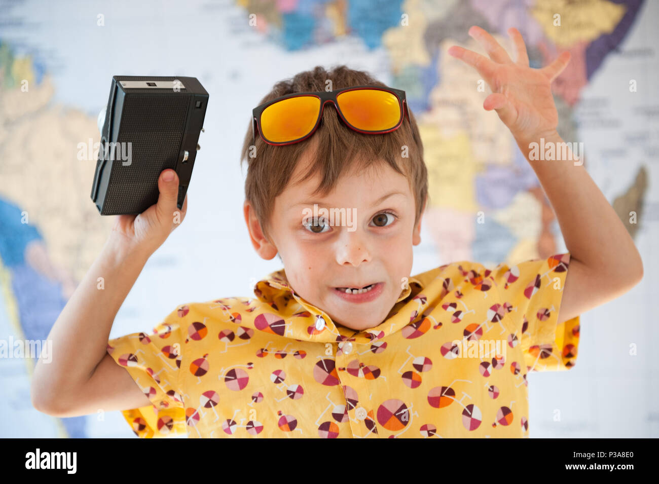 cute small boy in sunglasses with hands up holding retro vintage film