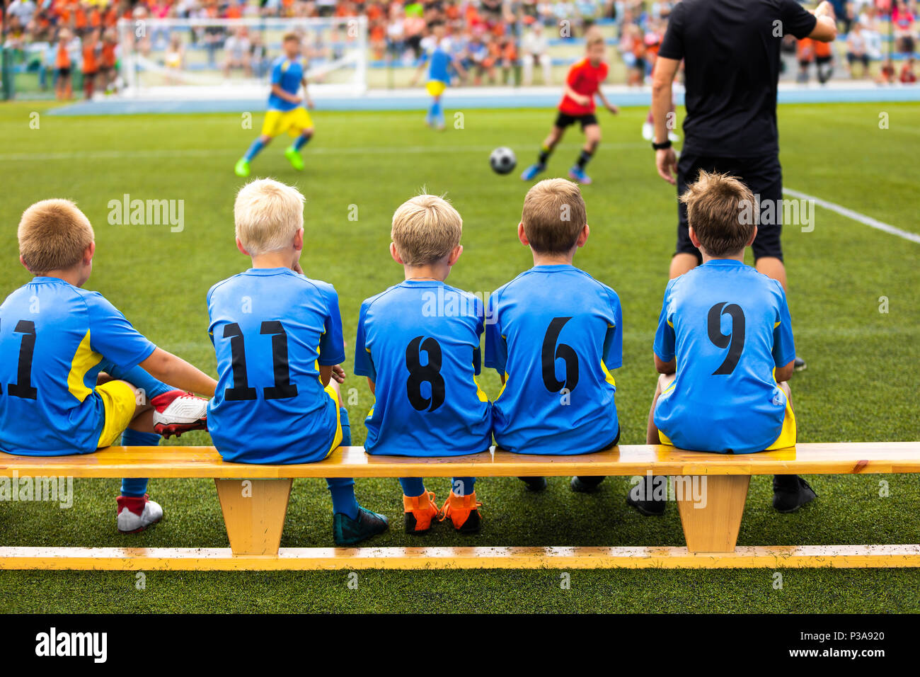 Football soccer game for children. Kids substitute players sitting on a bench. Football sports tournament for young boys Stock Photo