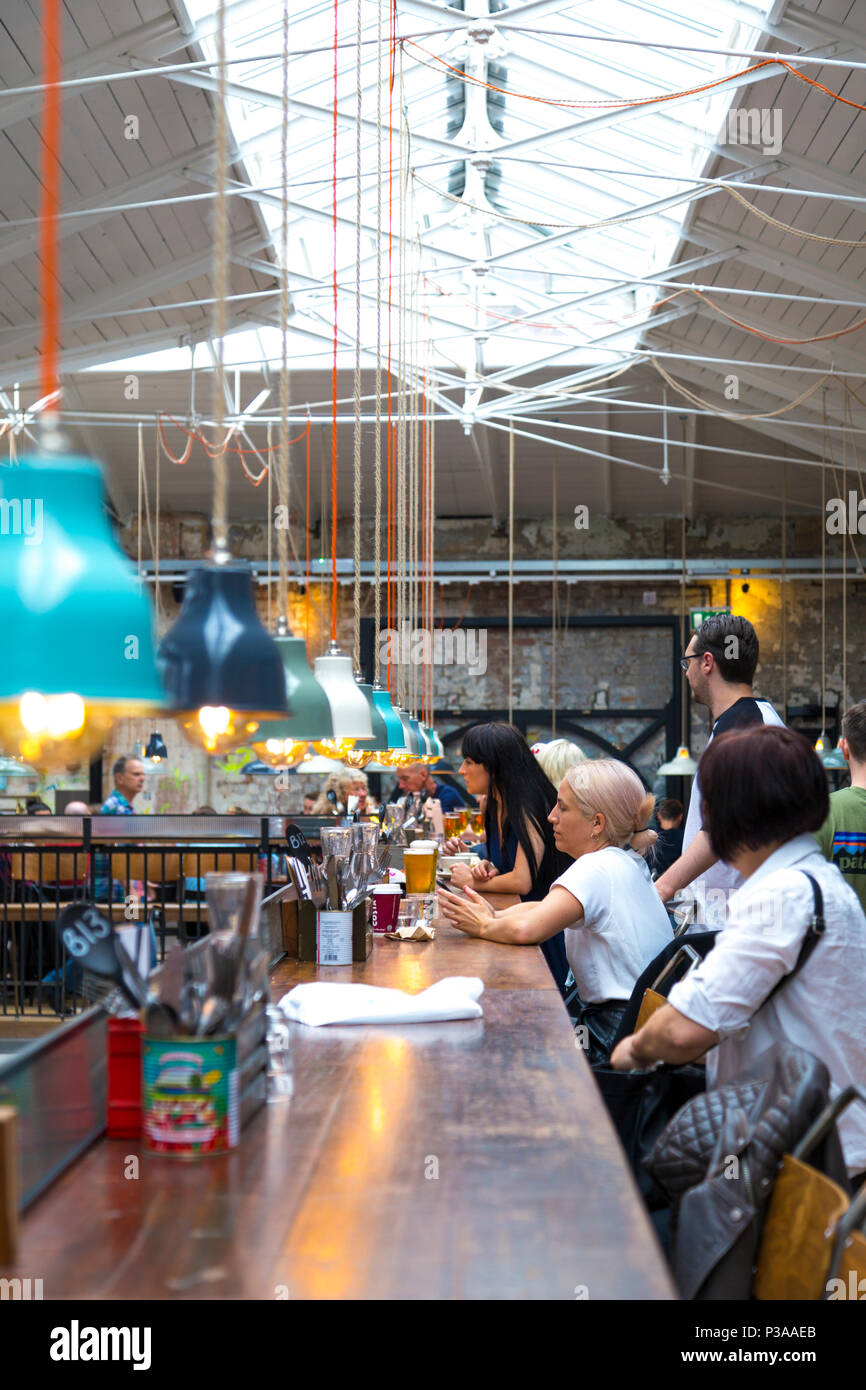 People eating in a food court, interior of Mackie Mayor inside a former meat market building in Manchester, UK Stock Photo