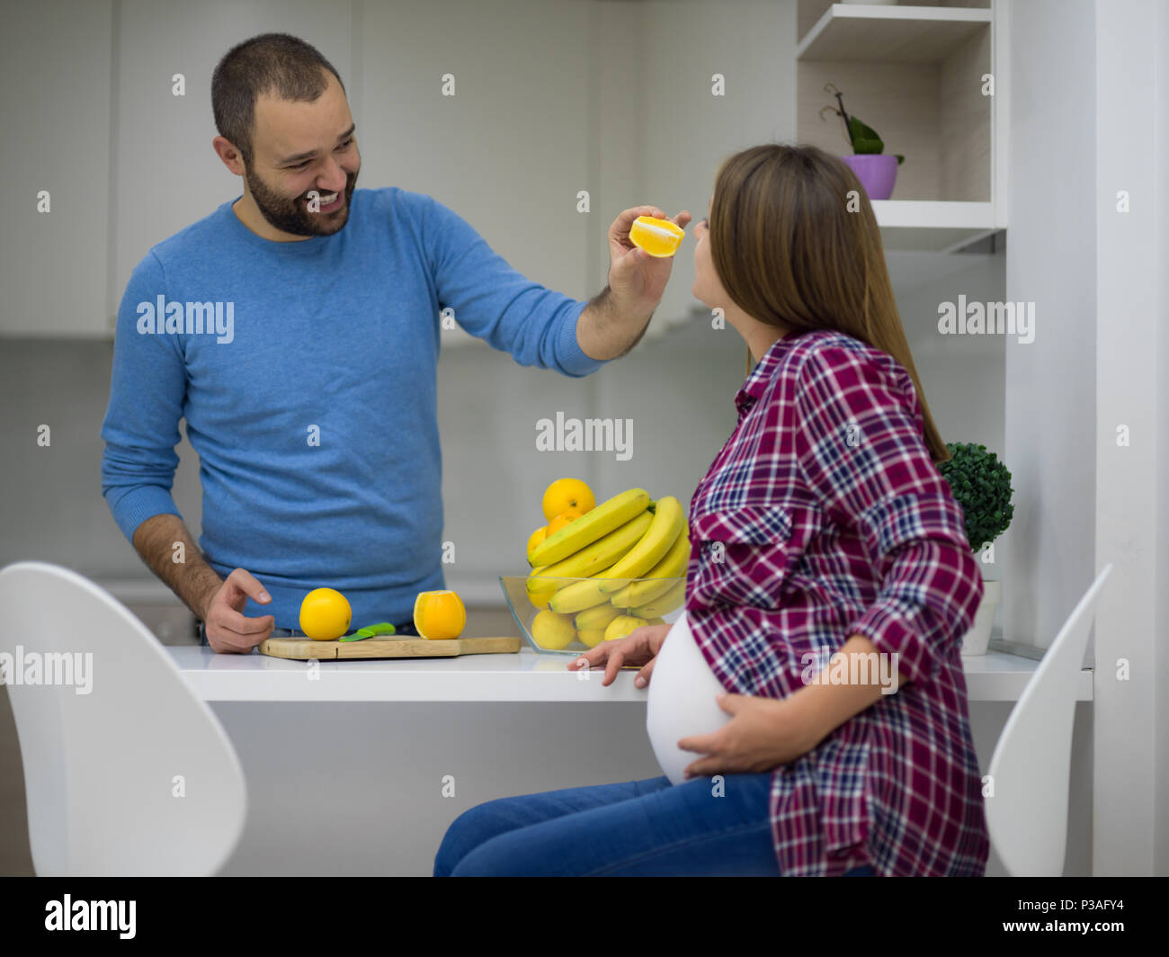 young pregnant couple cooking food fruit lemon juice at kitchen