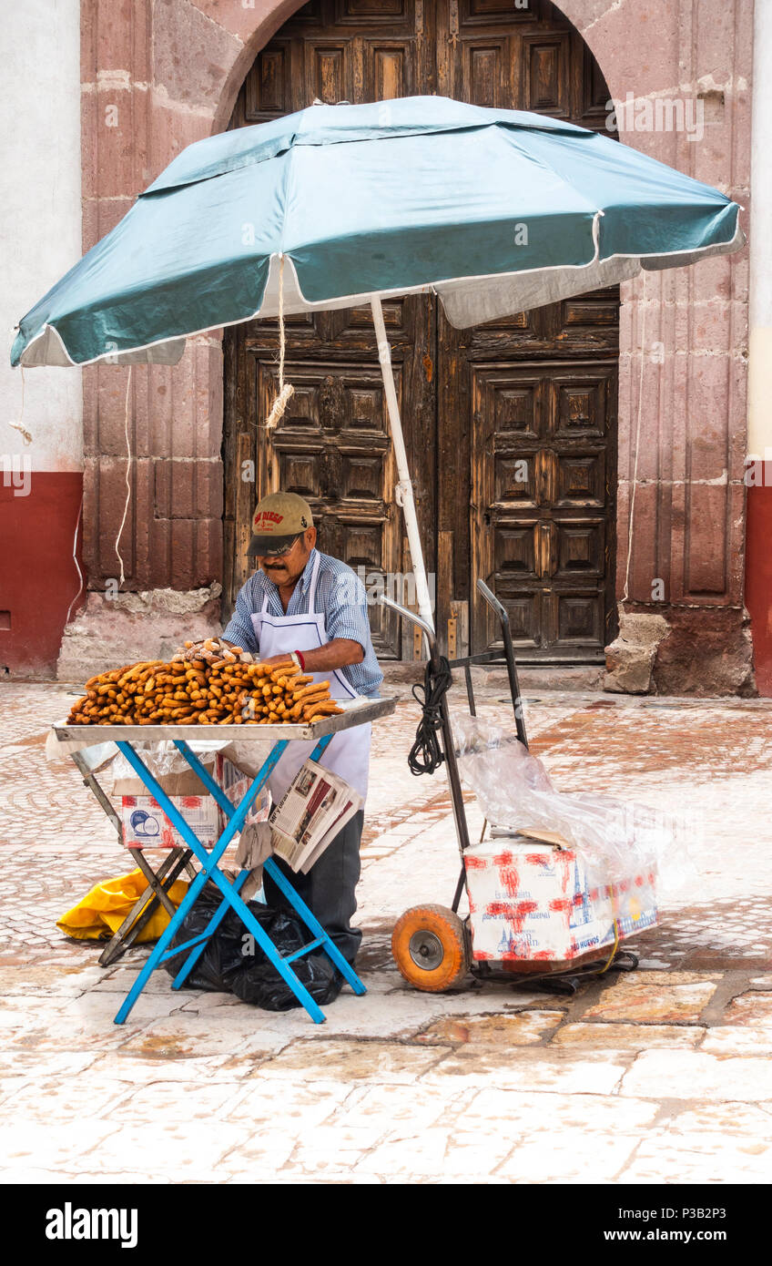 Man selling crullers at a street stand in San Miguel de Allende Stock Photo