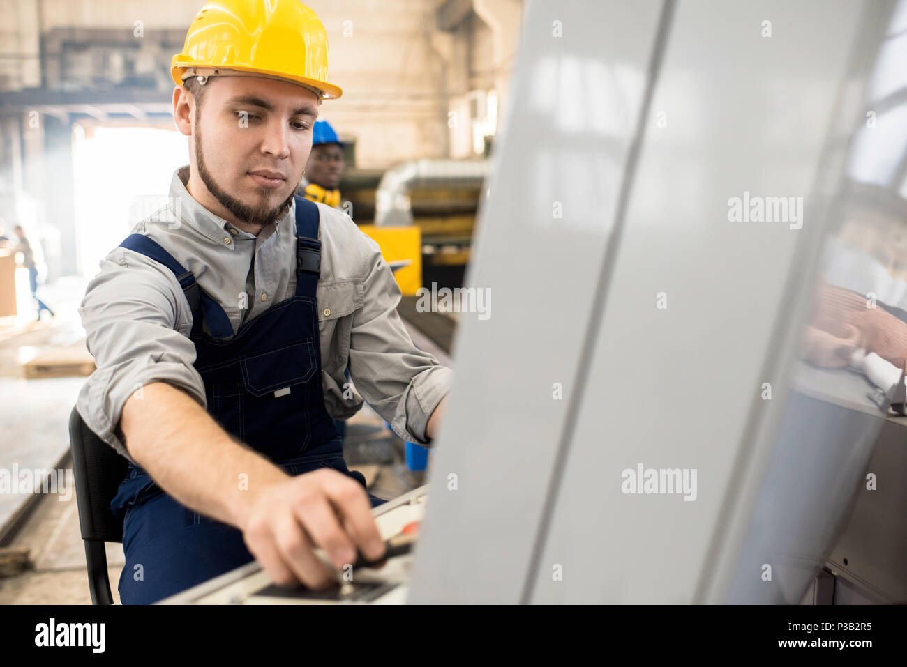 Concentrated worker operating manufacturing machine Stock Photo